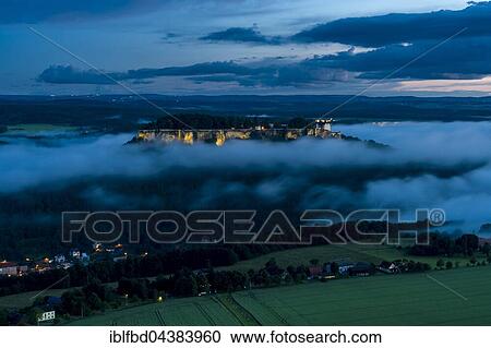 The illuminated fortress Festung Königstein, surrounded by clouds, seen from Lilienstein at night, Königstein, Saxony, Germany, Europe View Large Photo Image Stock Image - The illuminated fortress Festung Königstein, surrounded by clouds, seen from Lilienstein at night, Königstein, Saxony, Germany, Europe. Fotosearch