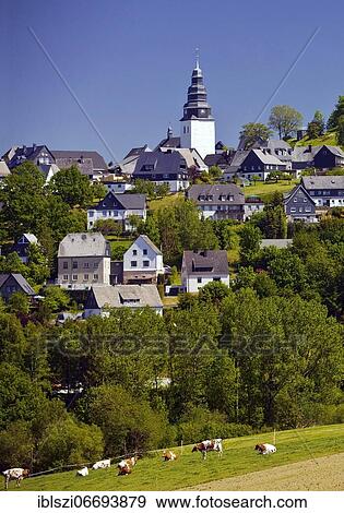 Stock Photo - The Saint John Evangelist Church with houses of Eversberg, Meschede, Sauerland, North Rhine-Westphalia, Germany, Europe. Fotosearch