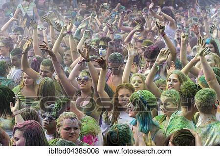 Stock Photo - Thousands of young women and man are raising their arms at the colorful Holi festival, Dresden, Saxony, Germany, Europe. Fotosearch
