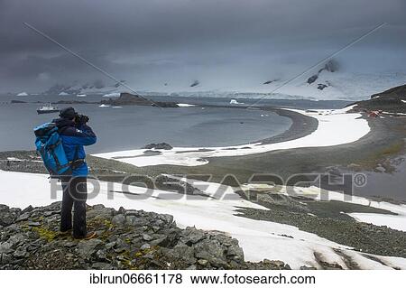 Tourist photographing from an overlook over Half moon island, South Sheltand islands, Antarctica View Large Photo Image Stock Photo - Tourist photographing from an overlook over Half moon island, South Sheltand islands, Antarctica. Fotosearch