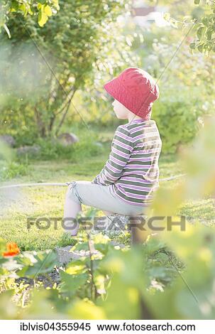 Stock Photography - Tranquil summer scene, young girl sitting in garden, watching plants and flowers, Sweden, Europe. Fotosearch