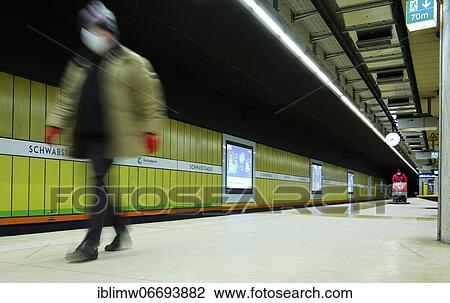 Stock Image - Traveller with mouth mask, waiting for arriving suburban train, behind him disinfection with scrubber-drier, Corona crisis, Schwabstraße, Stuttgart, Baden-Württemberg, Germany, Europe. Fotosearch