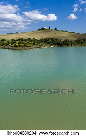 Typical green Tuscan landscape in Val d’Orcia, farm on hill, lake and blue cloudy sky, La Foce, Tuscany, Italy, Europe View Large Photo Image Picture - Typical green Tuscan landscape in Val d’Orcia, farm on hill, lake and blue cloudy sky, La Foce, Tuscany, Italy, Europe. Fotosearch