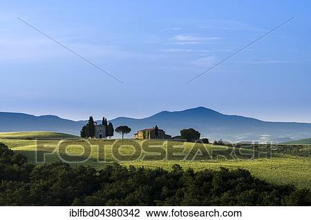Typical green Tuscan landscape in Val d’Orcia with farm and chapel on hill, fields, cypresses, trees and blue, cloudy sky, San Quirico d’Orcia, Tuscany, Italy, Europe View Large Photo Image Stock Image - Typical green Tuscan landscape in Val d’Orcia with farm and chapel on hill, fields, cypresses, trees and blue, cloudy sky, San Quirico d’Orcia, Tuscany, Italy, Europe. Fotosearch