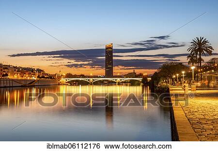 View over the river Rio Guadalquivir with illuminated bridge Puente de Triana and promenade, in the back skyscraper Torre Sevilla, sunset, blue hour, Sevilla, Andalusia, Spain, Europe View Large Photo Image Stock Photograph - View over the river Rio Guadalquivir with illuminated bridge Puente de Triana and promenade, in the back skyscraper Torre Sevilla, sunset, blue hour, Sevilla, Andalusia, Spain, Europe. Fotosearch