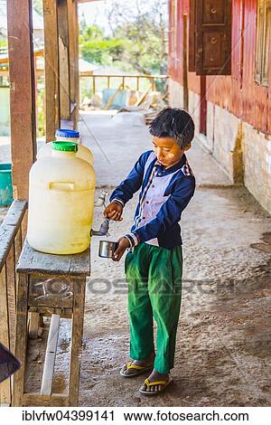 Stock Image - Young boy filling his cup with drinking water, pupil at school, Shan State, Myanmar, Asia. Fotosearch