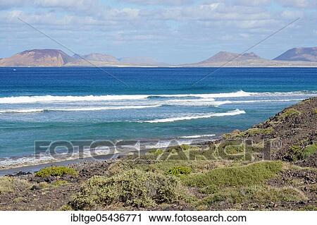 Stock Image - Beach at the cliffs of Famara, Riscos de Famara, view to the island La Graciosa, Lanzarote, Canary Islands, Spain, Europe. Fotosearch