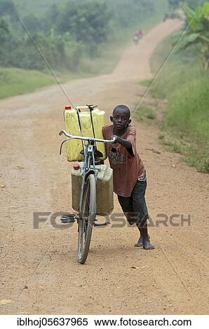 Boy pushing bicycle laden with full water containers along dusty road, Uganda, Africa View Large Photo Image Stock Photography - Boy pushing bicycle laden with full water containers along dusty road, Uganda, Africa. Fotosearch