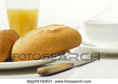 Stock Image - Breakfast, bread roll and orange juice, bread roll, knife. Fotosearch