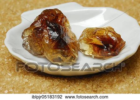 Stock Image - Brown rock candy and brown cane sugar, sweet, sugar crystals, rock candy. Fotosearch