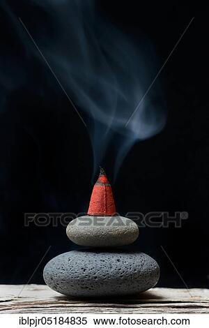 Stock Photography - Burning incense cone on stones, incense candle. Fotosearch