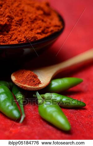 Stock Photograph - ( Capsicum annuum) Chilli powder in bowl and spoon and green chillies, paprika powder, chillies, kitchen spice, peppers. Fotosearch