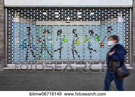 Stock Photo - Closed fashion store, bars in front of shop window, customer with mouth mask, lockdown, Corona crisis, Stuttgart, Baden-Württemberg, Germany, Europe. Fotosearch