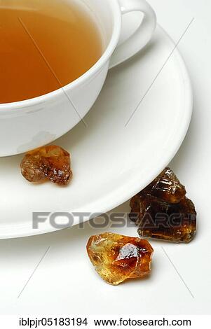 Picture - Cup of tea and brown rock candy, sweet, rock candy. Fotosearch