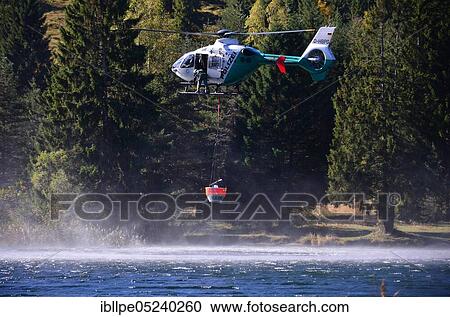 Stock Image - Fire fighting, police helicopter, water tank, filling. Fotosearch