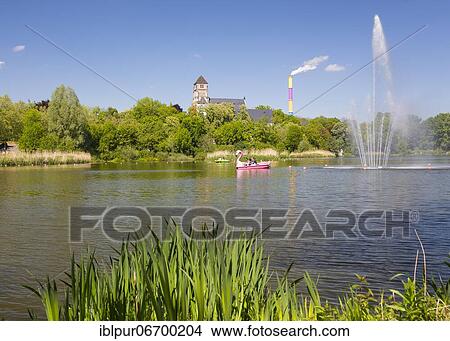 Picture - Fountain on the castle pond with Schlossberg church, in the background the colorful chimney of eins energie, Chemnitz, Saxony, Germany, Europe. Fotosearch