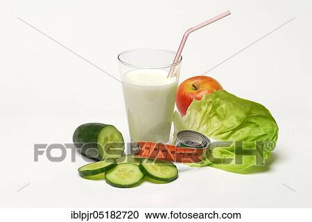 Stock Image - Glass of buttermilk, cucumber, lettuce leaf and apple, milk, straw, lettuce, lettuce, cucumber, measuring tape. Fotosearch