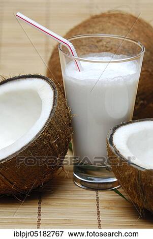 Stock Photo - Glass of coconut milk, halved coconut, drinking straw, coconut milk. Fotosearch