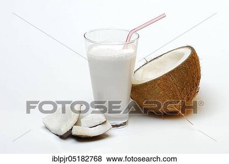 Stock Photo - Glass of coconut milk, halved coconut, drinking straw, coconut milk, coconut pieces. Fotosearch