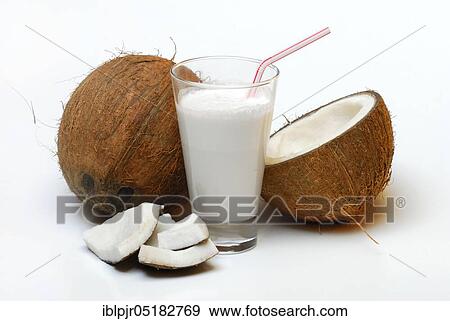 Stock Photo - Glass of coconut milk, halved coconut, drinking straw, coconut milk, coconut pieces. Fotosearch