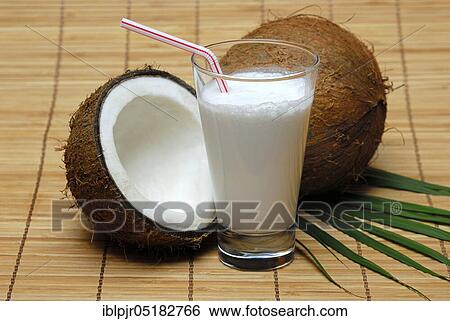 Stock Photograph - Glass of coconut milk, halved coconut, drinking straw, coconut milk. Fotosearch