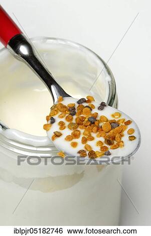 Stock Photograph - Glass of yoghurt, spoon with propolis, dairy products, natural yoghurt, flower pollen, bee resin, bee putty resin, putty wax, pollen, bee pollen, apitherapy. Fotosearch