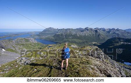 Stock Photography - Hiker on the trail to the mountain Rundfjellet, Lofoten, Nordland, Norway, Europe. Fotosearch