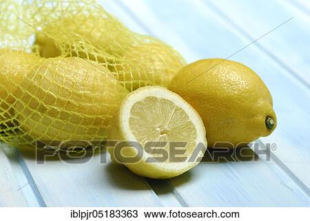 Stock Image - Lemons in a net, cut open, halved ( Citrus limon). Fotosearch