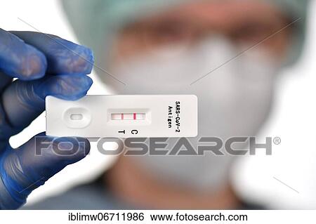 Stock Photograph - Medical staff shows positive antigen rapid test, test cassette, Corona crisis, Germany, Europe. Fotosearch