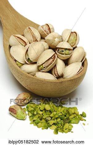 Stock Image - Real Pistachios (Pistacia vera), chopped seeds in wooden spoon. Fotosearch