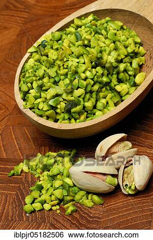 Stock Photograph - Real Pistachios (Pistacia vera), chopped seeds in wooden spoon. Fotosearch