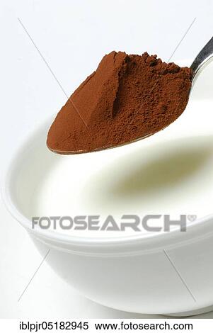 Stock Photography - Spoon of cocoa powder is put into cup with milk, cocoa drink, milk, milk products, cocoa. Fotosearch