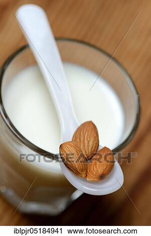 Stock Image - Spoon with almonds on glass of milk( Prunus dulcis), sweet almond. Fotosearch