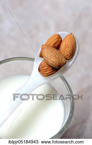 Stock Image - Spoon with almonds on glass of milk( Prunus dulcis), sweet almond. Fotosearch