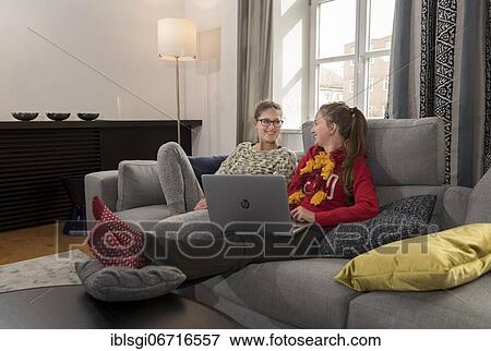 Stock Photo - Two young woman sitting on a sofa with a laptop. Fotosearch