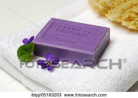 Stock Image - Violet soap and violet flowers on towel, soap. Fotosearch