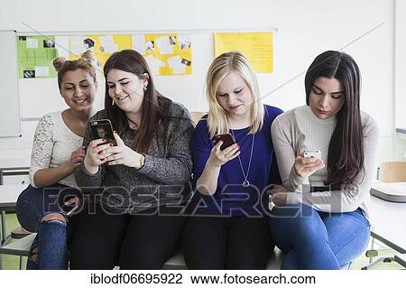 Stock Image - Vocational school students with their smartphones during break at the Elly-Heuss-Knapp-Schule, a vocational college of the city of Düsseldorf, North Rhine-Westphalia, Germany, Europe. Fotosearch