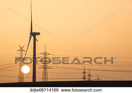 Wind turbine and power pole at sunset, Niederaussem, North Rhine-Westphalia, Germany, Europe View Large Photo Image Stock Photo - Wind turbine and power pole at sunset, Niederaussem, North Rhine-Westphalia, Germany, Europe. Fotosearch