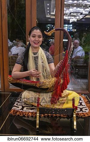 Woman playing a harp like instrument, Yangon, Myanmar, Asia View Large Photo Image Picture - Woman playing a harp like instrument, Yangon, Myanmar, Asia. Fotosearch