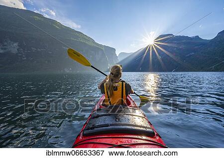 Stock Photo - Young woman paddling in a kayak, sun shining, Geirangerfjord, near Geiranger, Norway, Europe. Fotosearch