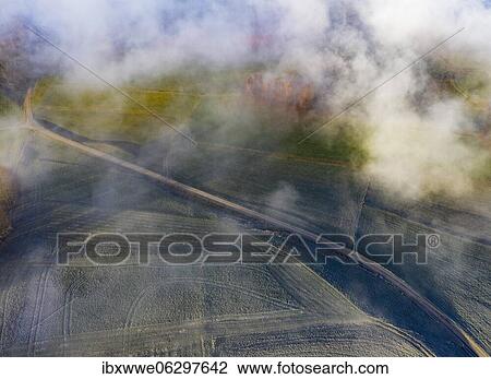 Stock Image - Country road through agricultural landscape covered with hoarfrost in morning fog, from above, drone shot, aerial view, Mondseeland, Salzkammergut, Upper Austria, Austria, Europe. Fotosearch