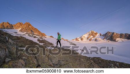 Stock Image - Evening mood, Alpine glow, Hiker in front of Glacier du Tour, Glacier and mountain peaks, High Alpine landscape, Tête Blanche, Petite and Grande Fourche on the left, Aiguille du Chardonnet on the right, Chamonix, Haute-Savoie, France, Europe. Fotosearch