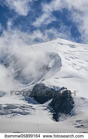 Picture - High alpine mountain landscape, clouds on the summit Dôme du Goûter with glacier, Chamonix, Haute-Savoie, France, Europe. Fotosearch