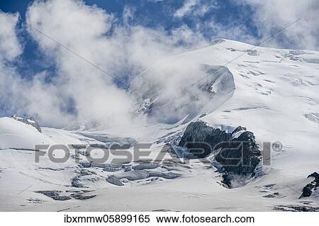Stock Photography - High alpine mountain landscape, clouds on the summit Dôme du Goûter with glacier, Chamonix, Haute-Savoie, France, Europe. Fotosearch