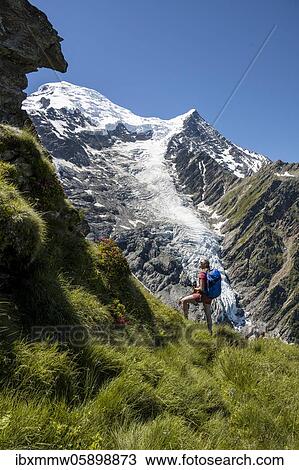 Stock Image - Hiker in front of glacier, hiking trail La Jonction, glacier Glacier de Taconnaz, summit of Mont Blanc and Aiguille de Bionnassay, right Mont Blanc, Chamonix, Haute-Savoie, France, Europe. Fotosearch
