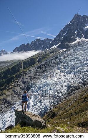 Stock Photo - Hiker in front of glacier tongue, Glacier des Bossons, left summit of Aiguille du Midi, Chamonix, Haute-Savoie, France, Europe. Fotosearch