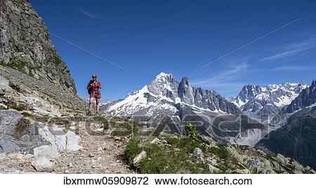 Stock Image - Hiker on hiking trail, Grand Balcon Sud, glacier, Mer de Glace, Aiguille Verte summit, Grandes Jorasses, Mont Blanc massif, Chamonix-Mont-Blanc, Haute-Savoie, France, Europe. Fotosearch