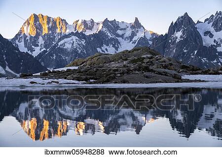 Stock Photo - Morning atmosphere at sunrise, water reflection in Lac Blanc, mountain top, Aiguille Verte, Grandes Jorasses, Aiguille du Moine, Mont Blanc, Mont Blanc massif, Chamonix-Mont-Blanc, Haute-Savoie, France, Europe. Fotosearch
