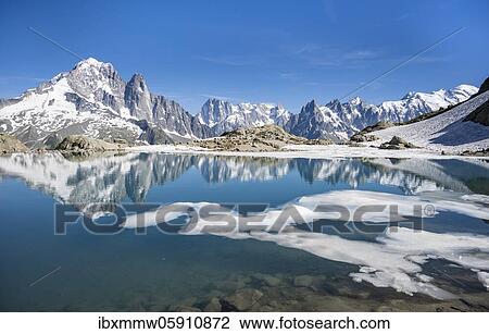 Stock Image - Mountain panorama, ice floe on Lac Blanc, mountain peaks reflected in mountain lake, Grandes Jorasses and Mont Blanc massif, Chamonix-Mont-Blanc, Haute-Savoie, France, Europe. Fotosearch