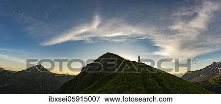 Stock Photo - Mountaineer on mountain meadow of the Habart ridge in the foreground with mountains of the Maldongrat in the background at sunrise, Elmen, Lechtaler Alps, Außerfern, Tyrol, Austria, Europe. Fotosearch